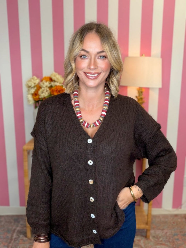 woman standing in a room in a brown sweater