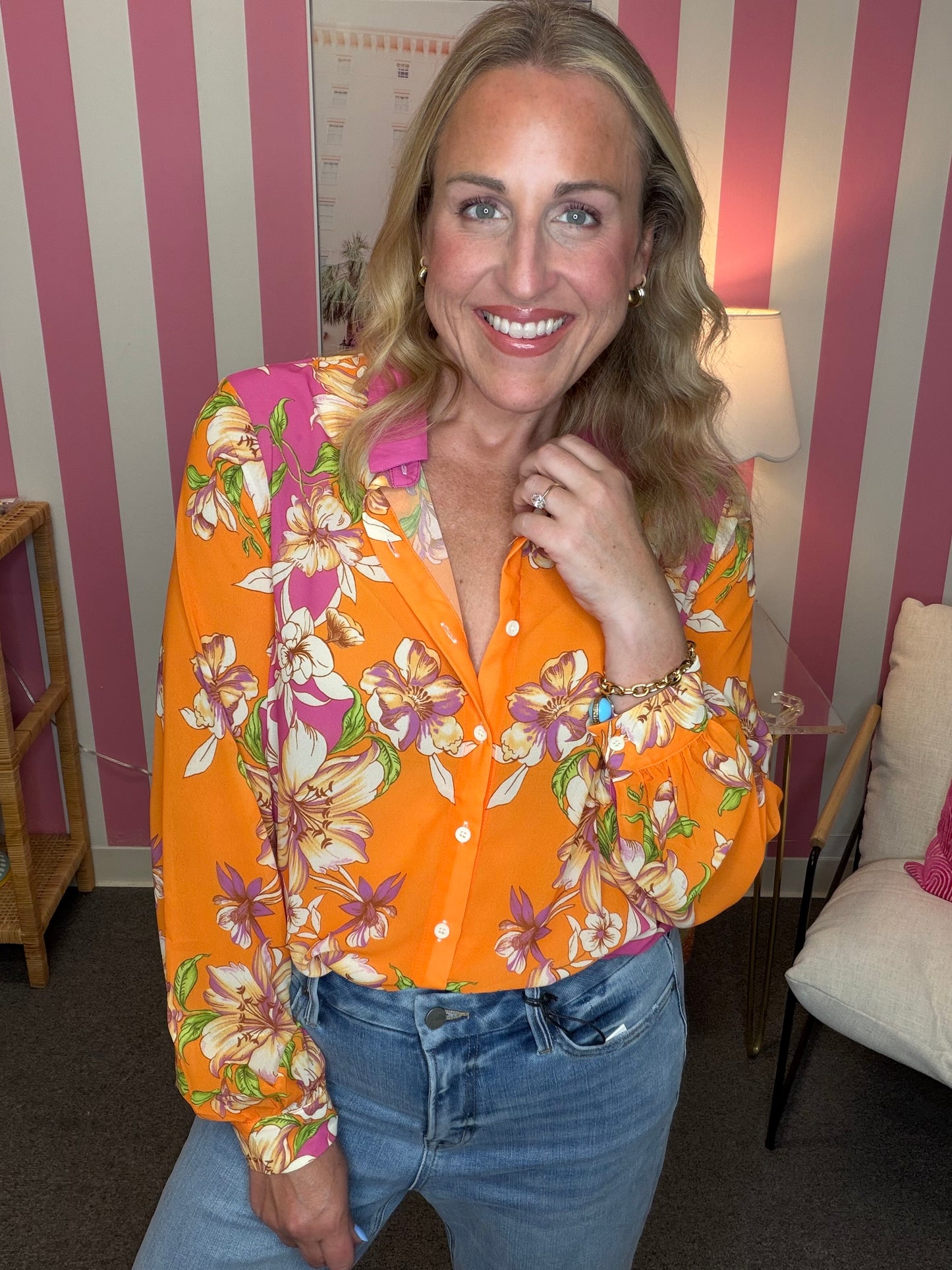 Woman wearing a colorful floral shirt in a room with striped walls.