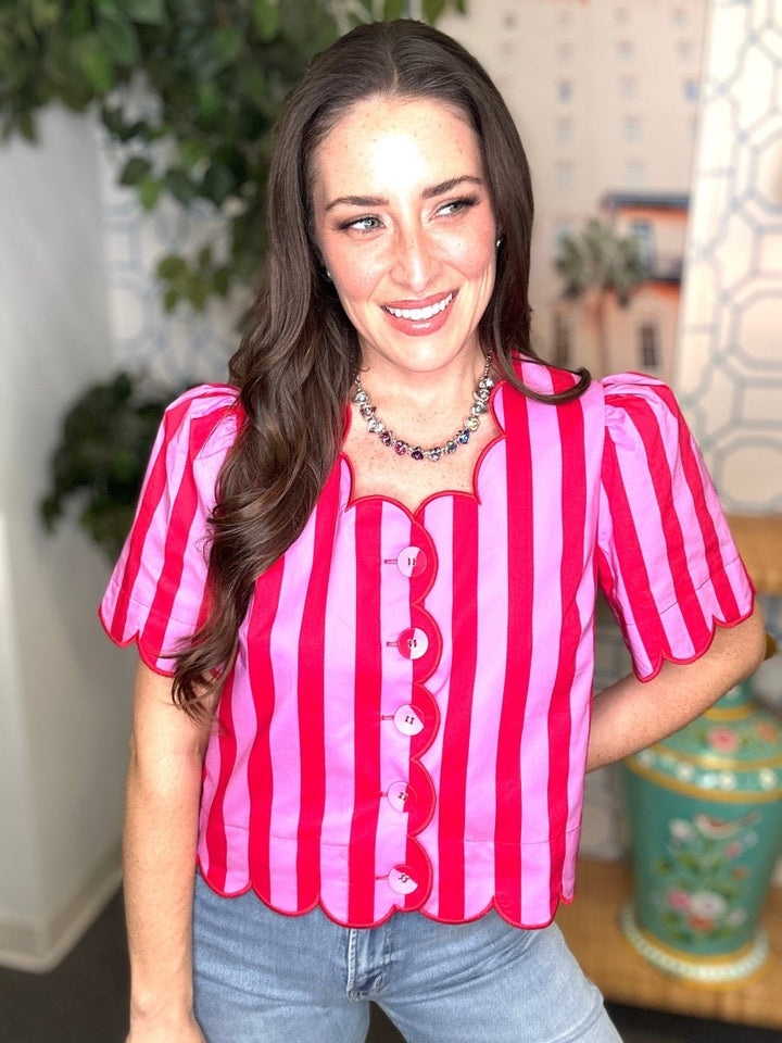Woman wearing a red and pink striped shirt with a blurred indoor background