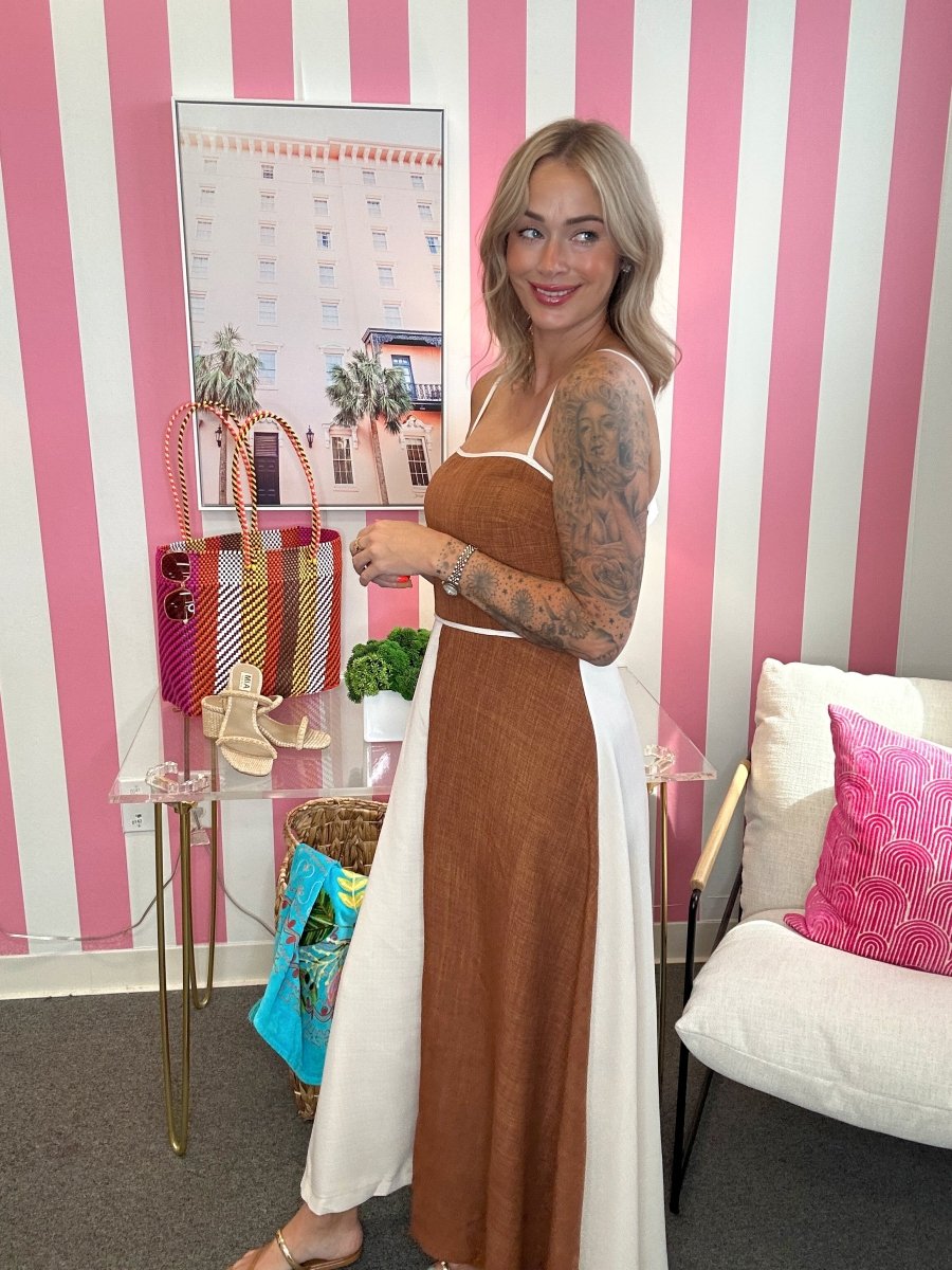 Woman standing in a room with pink and white striped walls, holding a glass of wine.