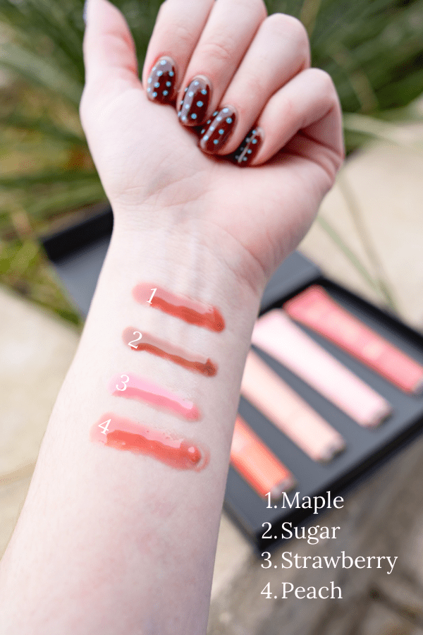 Lipstick swatches on a person's wrist with a lipstick case in the background