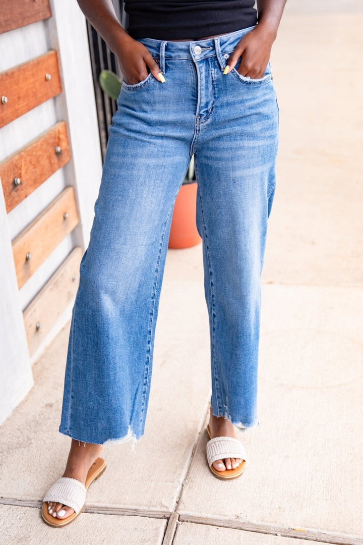 Person wearing blue jeans standing on a tiled floor.
