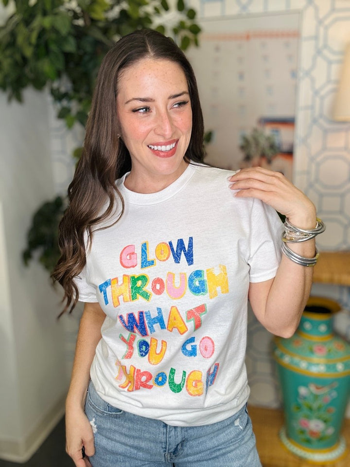 Woman wearing a white t-shirt with colorful text in a home setting