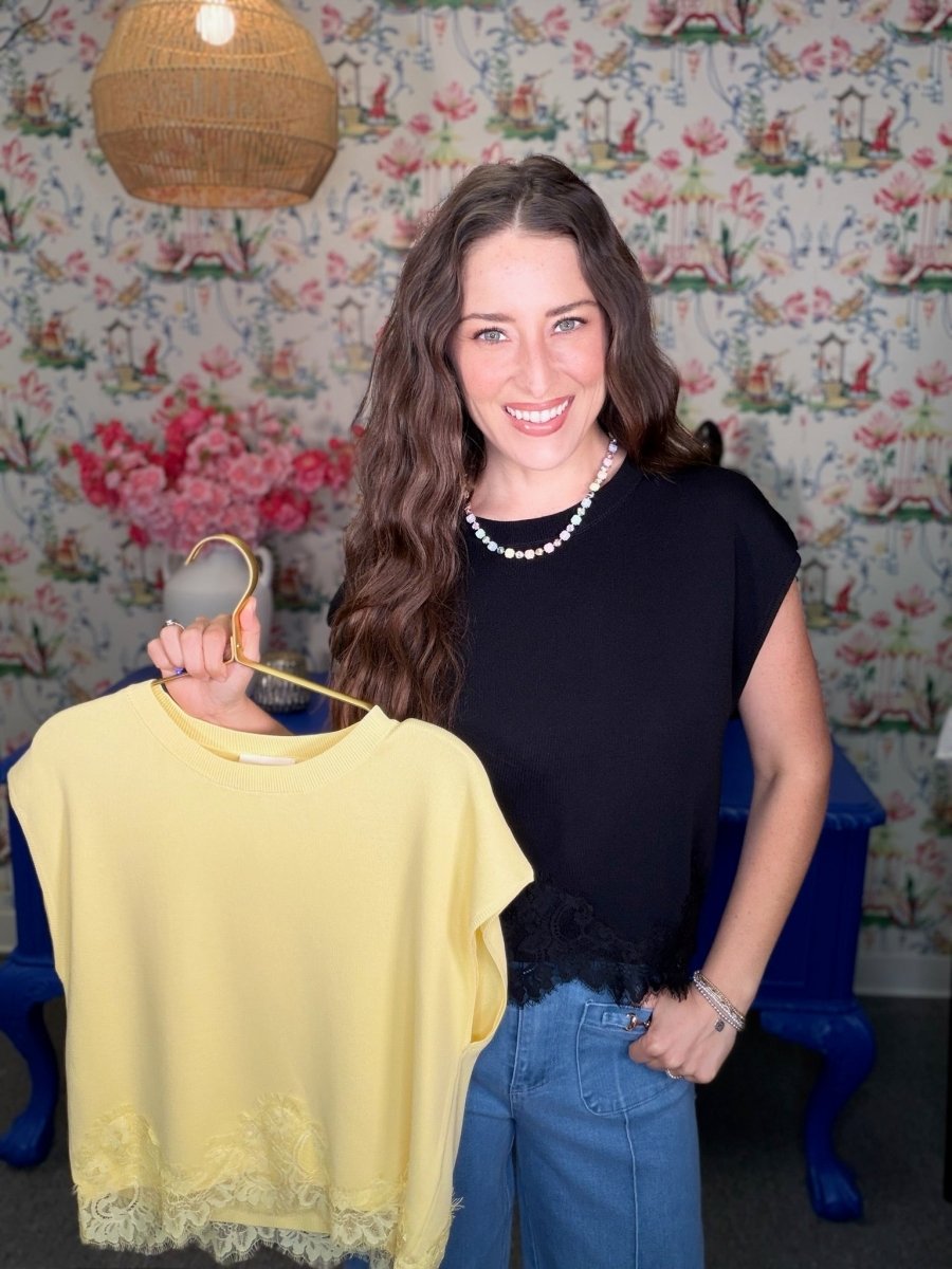 Woman holding a yellow top in front of floral wallpaper