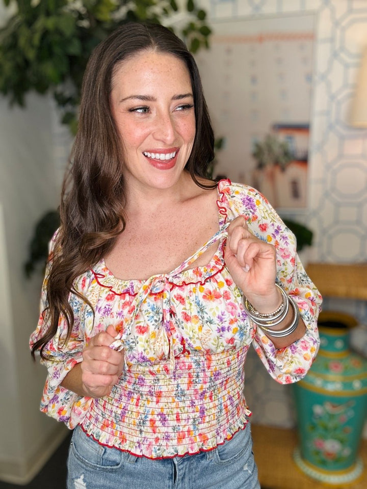 Woman wearing a colorful floral blouse in an indoor setting