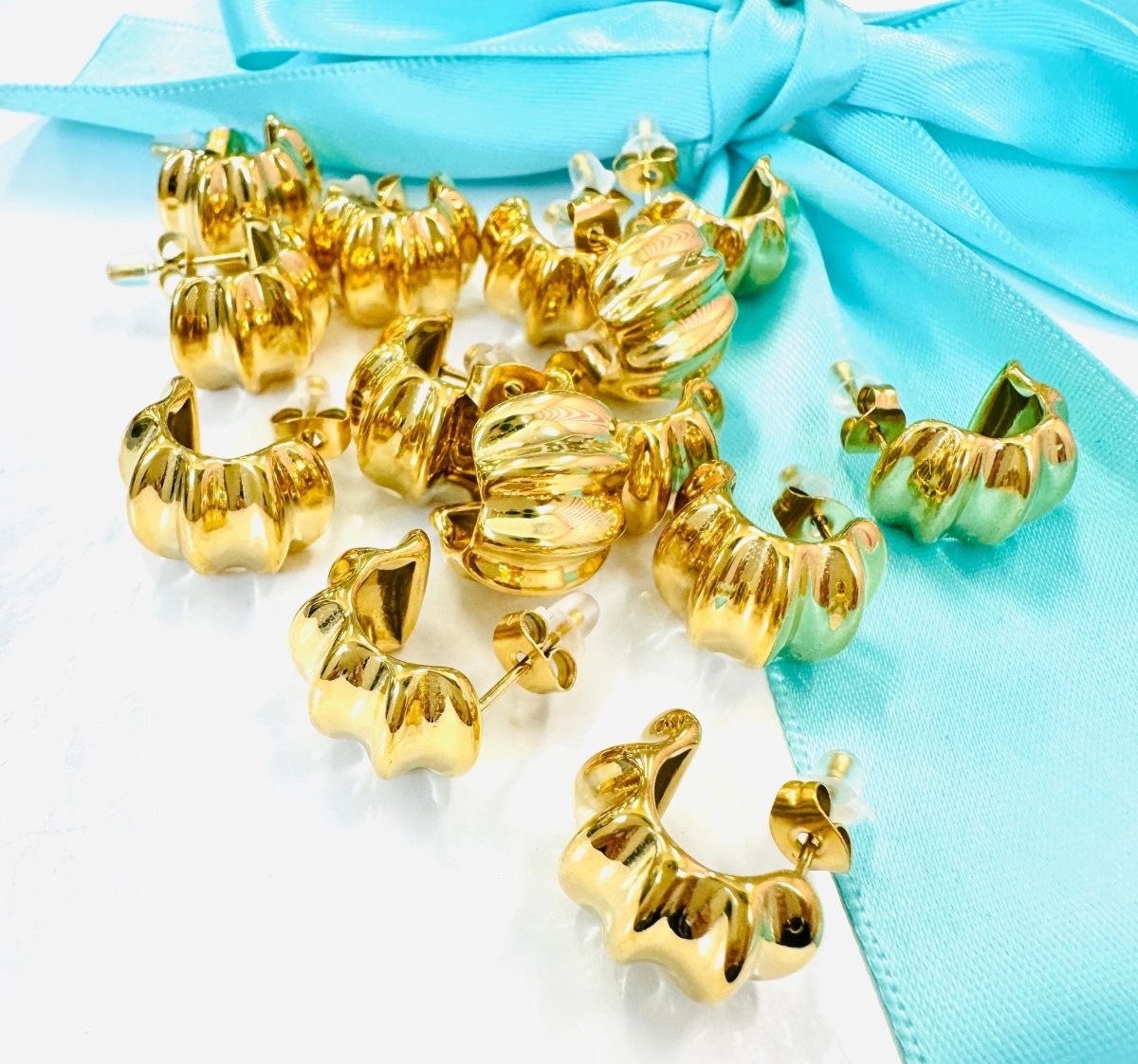 Gold hoop earrings on a light blue fabric background