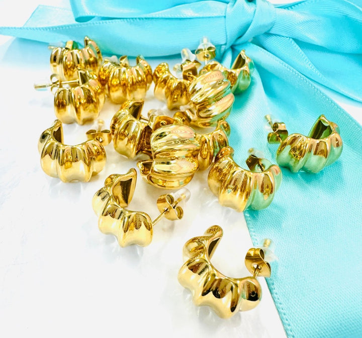 Gold hoop earrings on a light blue fabric background