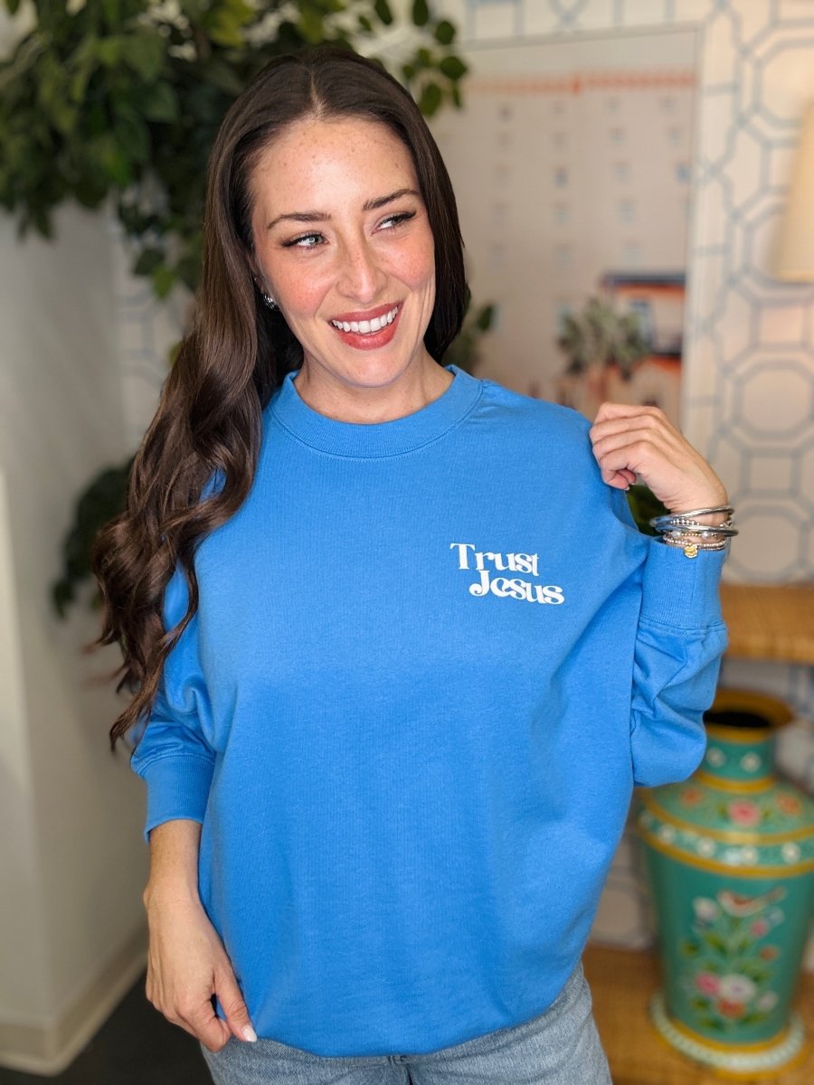 Woman wearing a blue sweatshirt with 'True Jesus' text in a home setting