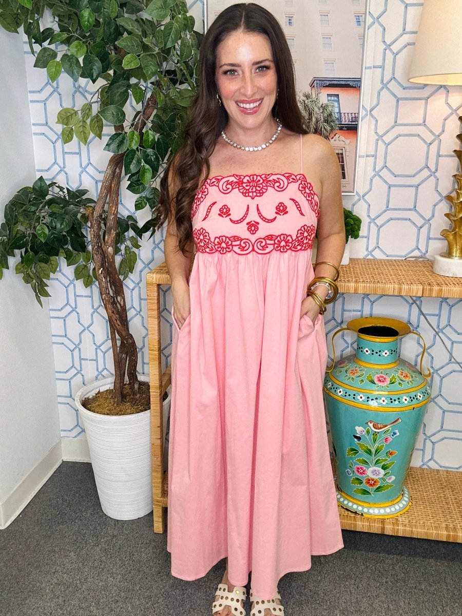 Woman in a pink dress standing in a room with decorative elements.