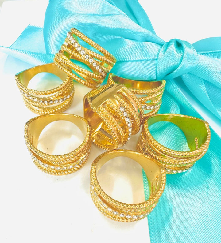 Gold rings with intricate designs on a turquoise fabric background