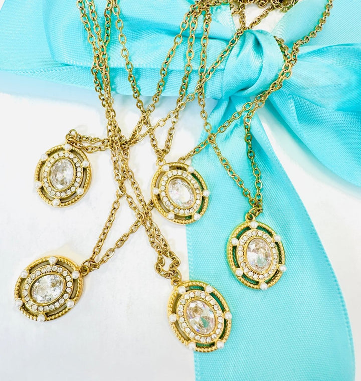 Gold necklaces with intricate pendants on a turquoise ribbon