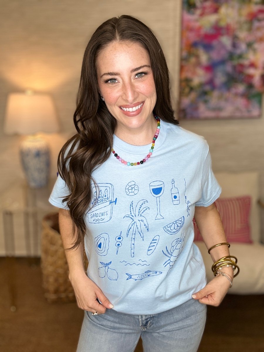 Woman wearing a light blue t-shirt with graphics in a living room setting