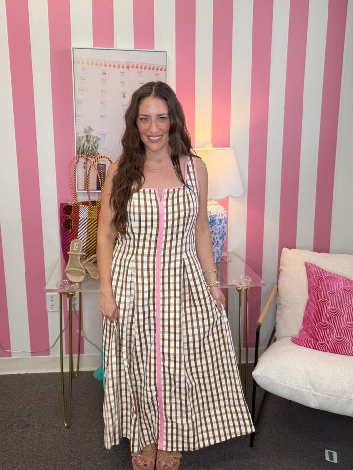 Woman in a checkered dress standing in a room with pink and white striped walls.