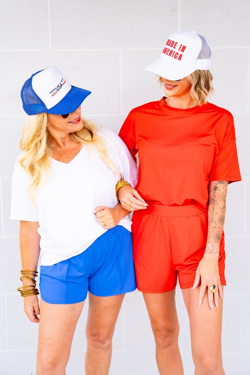 Two women wearing matching outfits with hats against a white background
