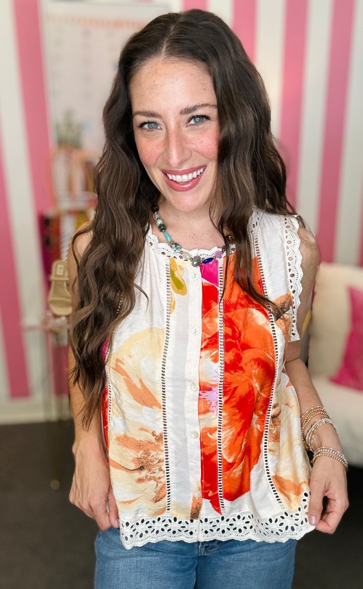 Woman wearing a colorful sleeveless top with a floral pattern in a casual setting.