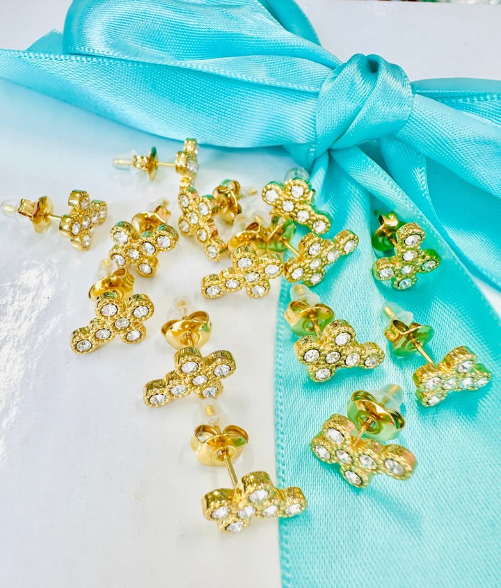 Gold and green bow-shaped earrings on a turquoise ribbon