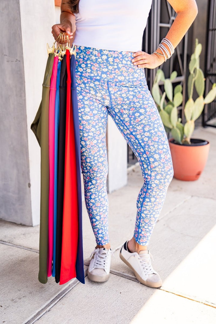 Person holding colorful leggings with a cactus plant in the background