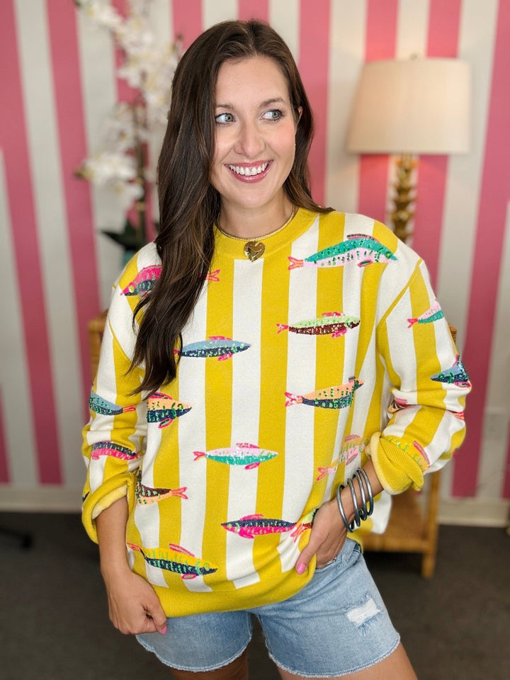 Woman wearing a yellow and white patterned sweater with a striped background