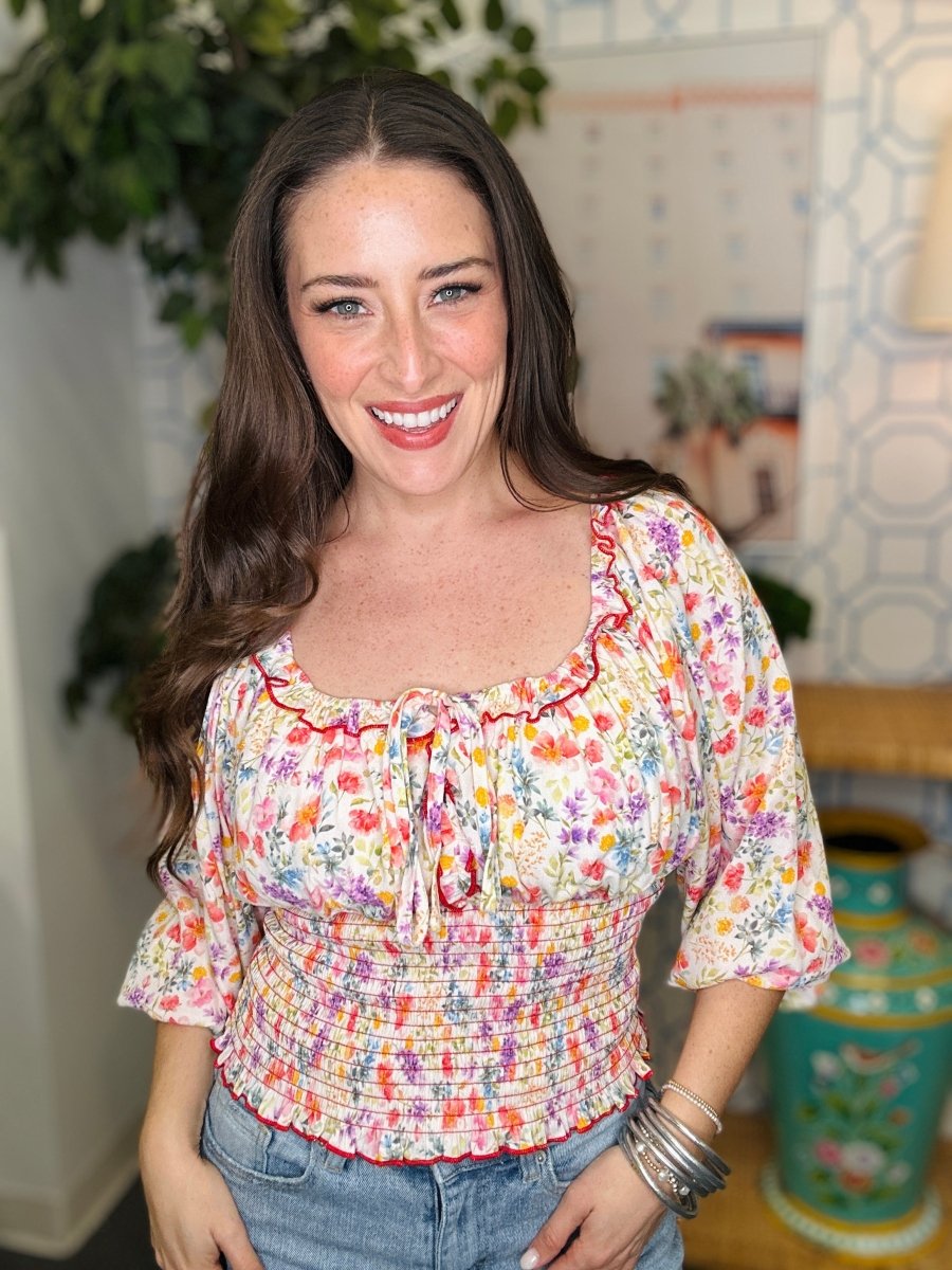 Woman wearing a colorful floral blouse in an indoor setting