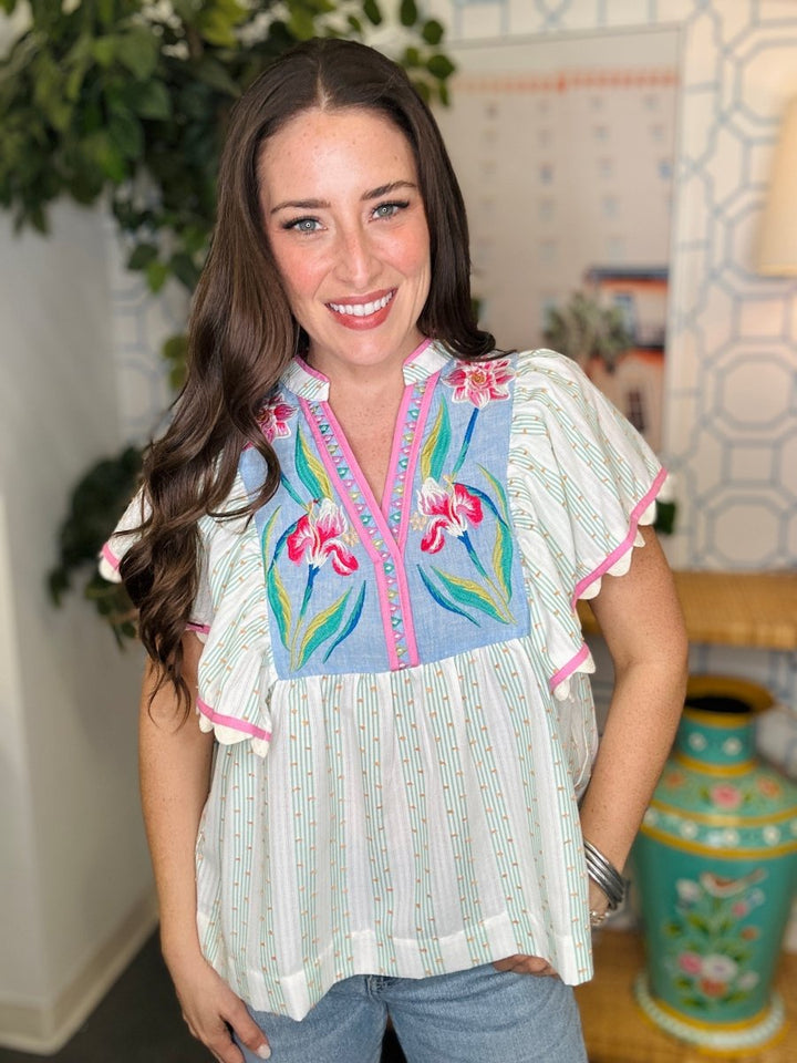 Woman wearing a colorful embroidered blouse in an indoor setting