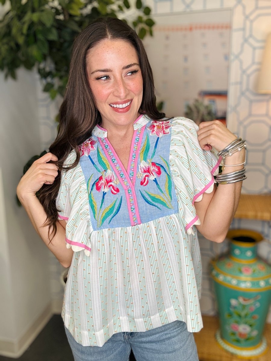 Woman wearing a colorful embroidered blouse in an indoor setting