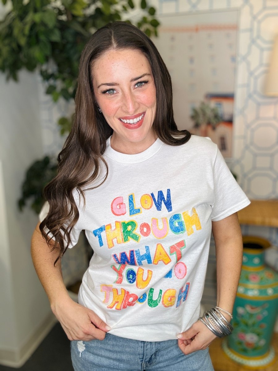 Woman wearing a white t-shirt with colorful text in a casual setting