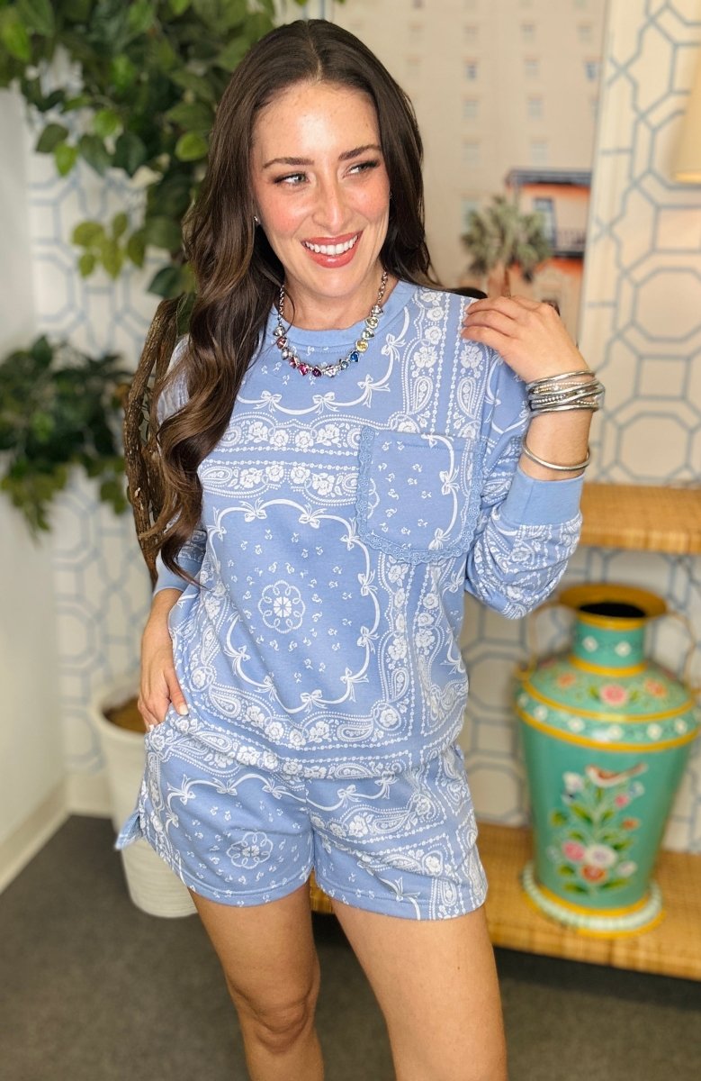 Woman wearing a blue patterned outfit standing in a room with decorative elements.