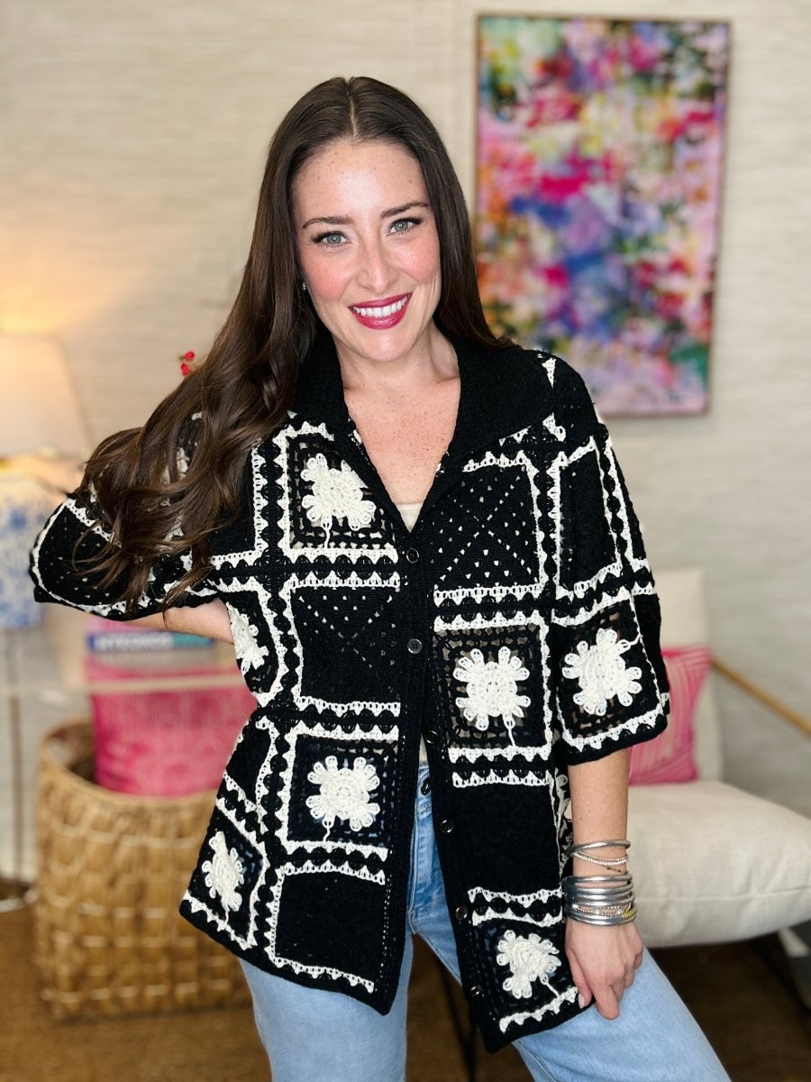 Woman wearing a black and white patterned jacket in a living room setting.