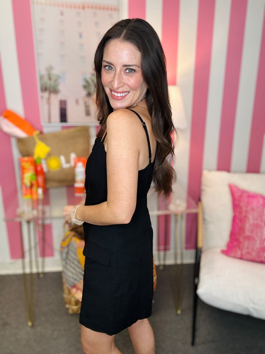Woman in a black dress standing in a room with pink and white striped walls.
