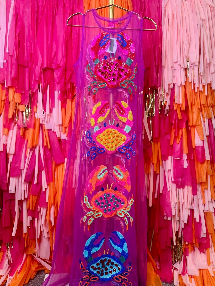 Colorful embroidered dress on a hanger with a vibrant, multicolored fringe background.