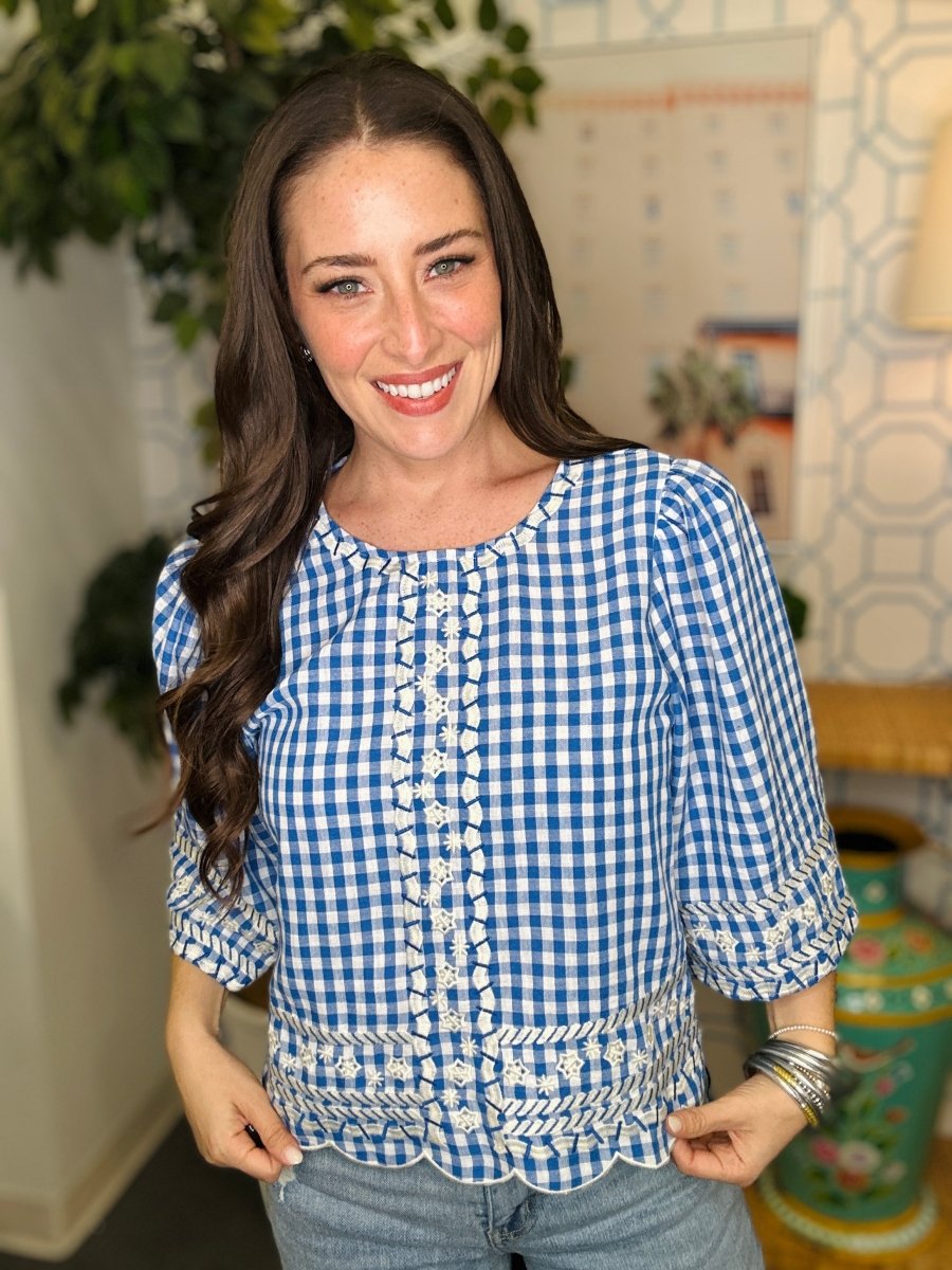 Woman wearing a blue and white checkered blouse in an indoor setting