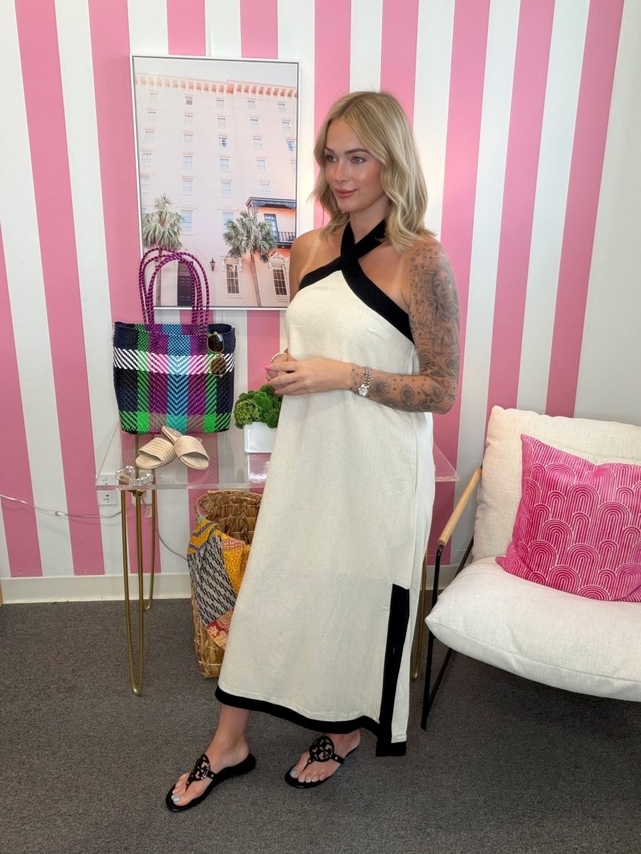 Woman in a white dress with black accents standing in a room with pink and white striped walls.