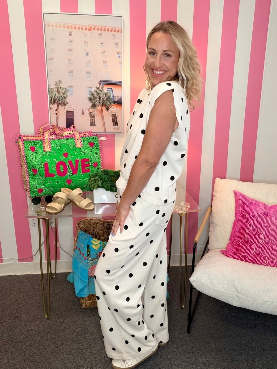 Woman in a polka dot outfit standing in a room with pink and white striped walls.