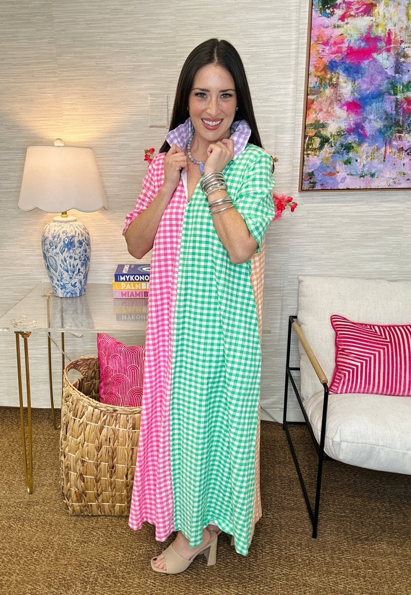 Woman holding a pink and green checkered scarf in a living room setting.