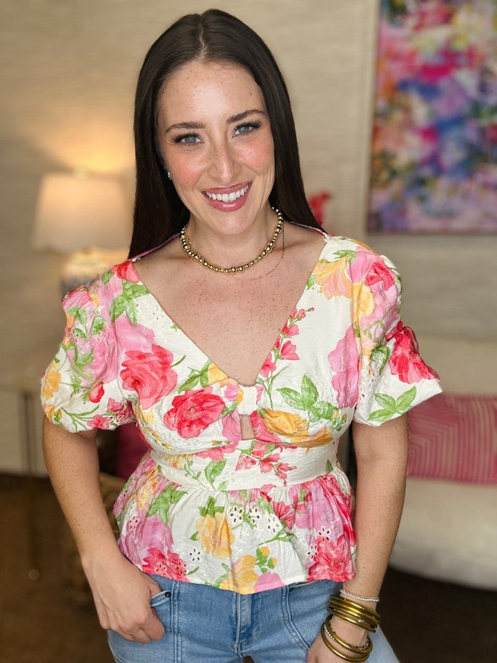 Woman wearing a floral top in a room with a colorful painting on the wall.