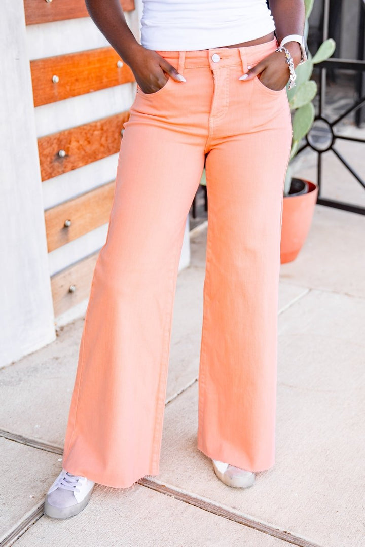 Person wearing peach flared jeans standing on a patio.