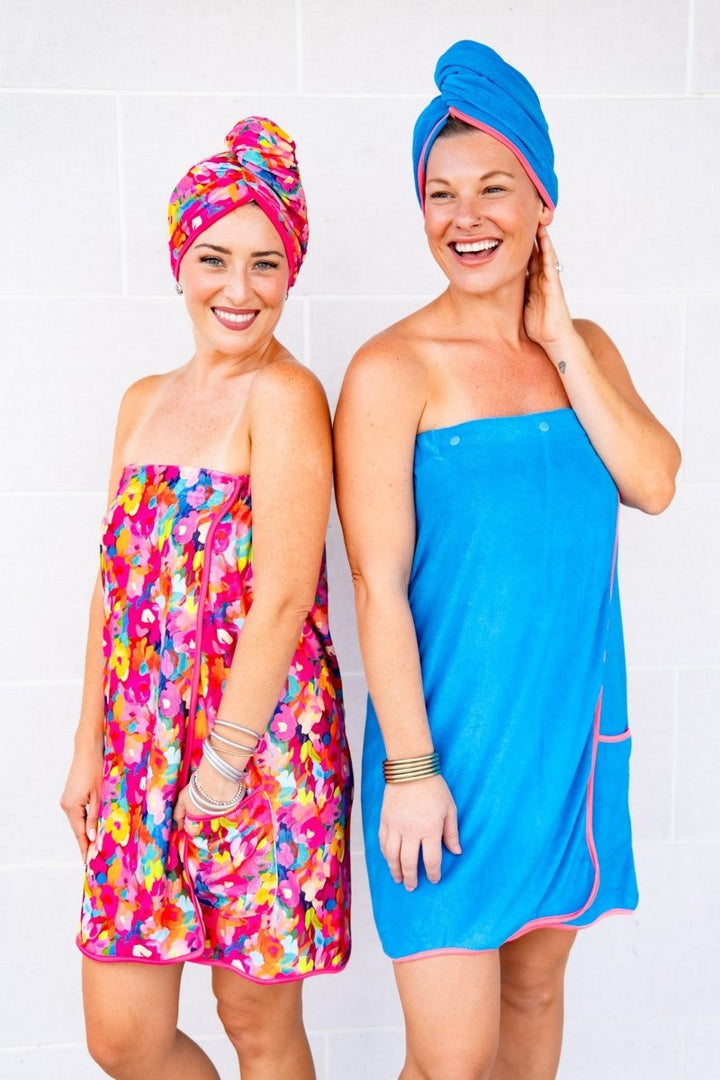 Two women wearing colorful towel wraps against a white background