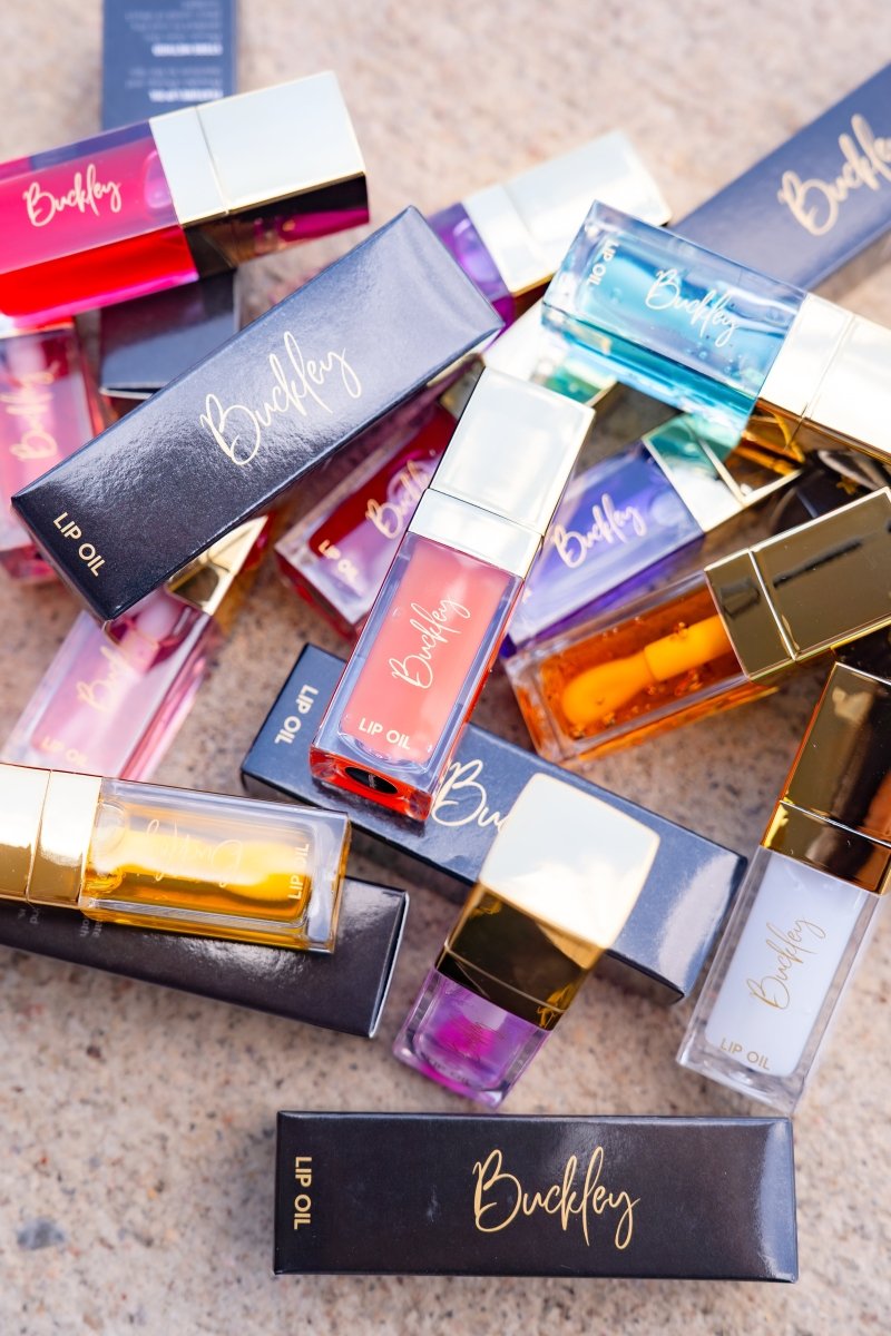 Collection of Buckley lip oils in various colors on a textured surface