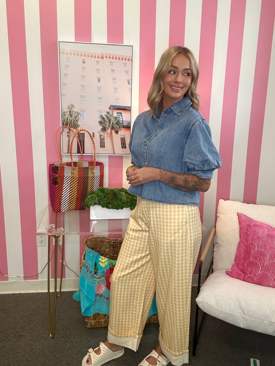 Woman standing in a room with pink and white striped walls, holding a plant.