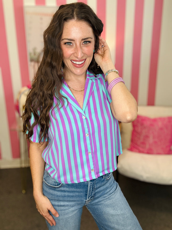 Woman wearing a purple and white striped shirt with jeans indoors.