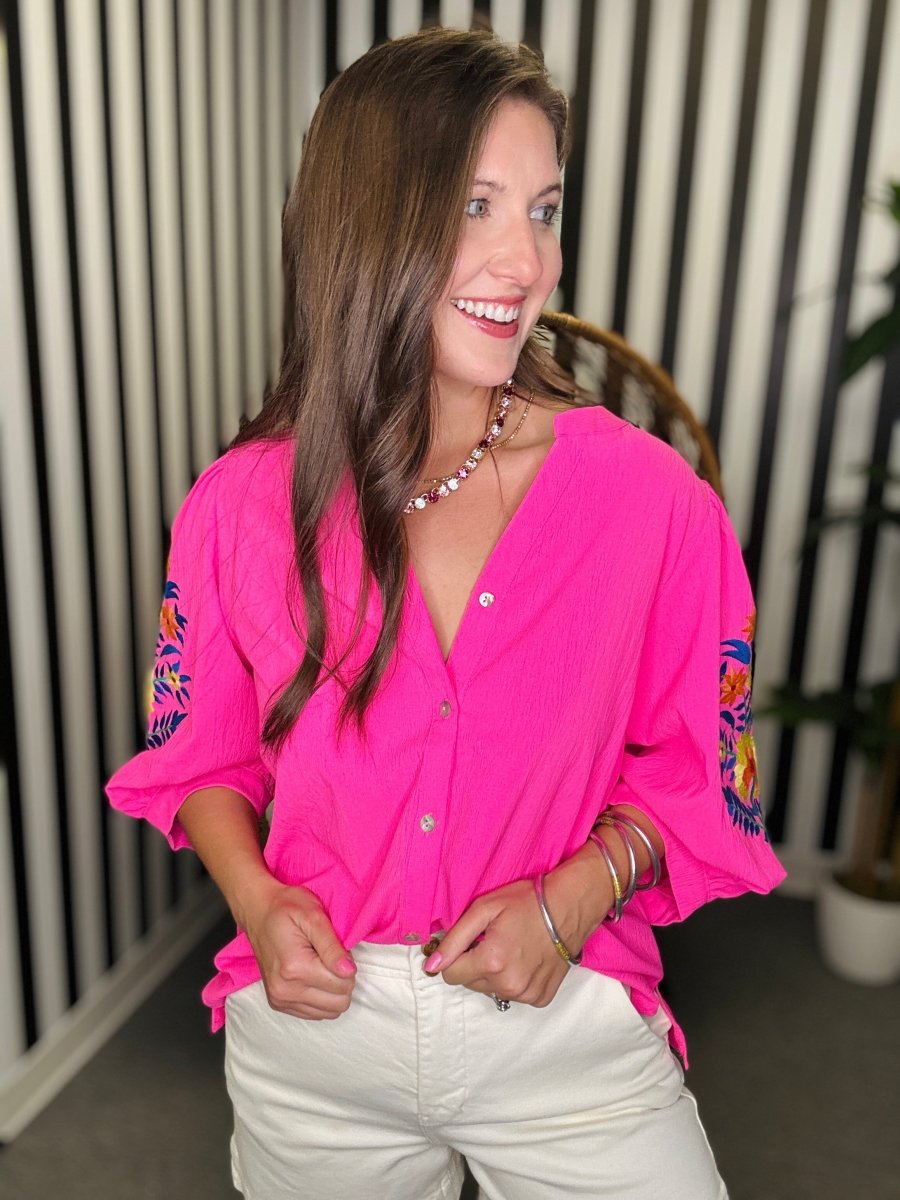 Woman wearing a bright pink blouse with colorful sleeves indoors.