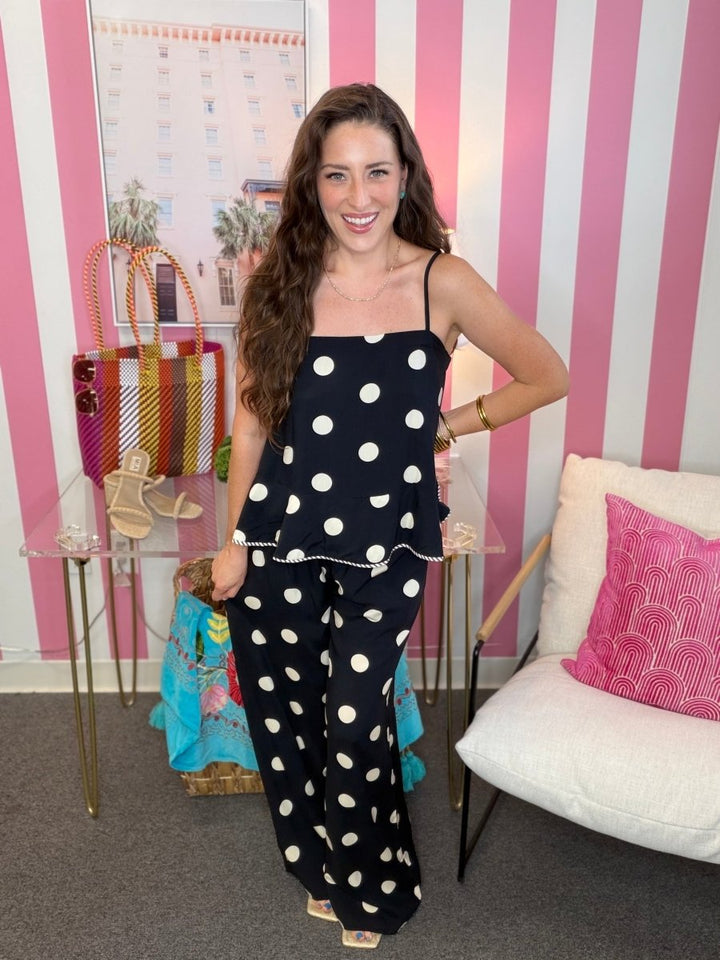 Woman in a polka dot outfit standing in a room with striped walls and furniture.