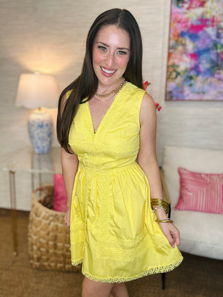 Woman in a yellow dress standing in a room with a couch and lamp.