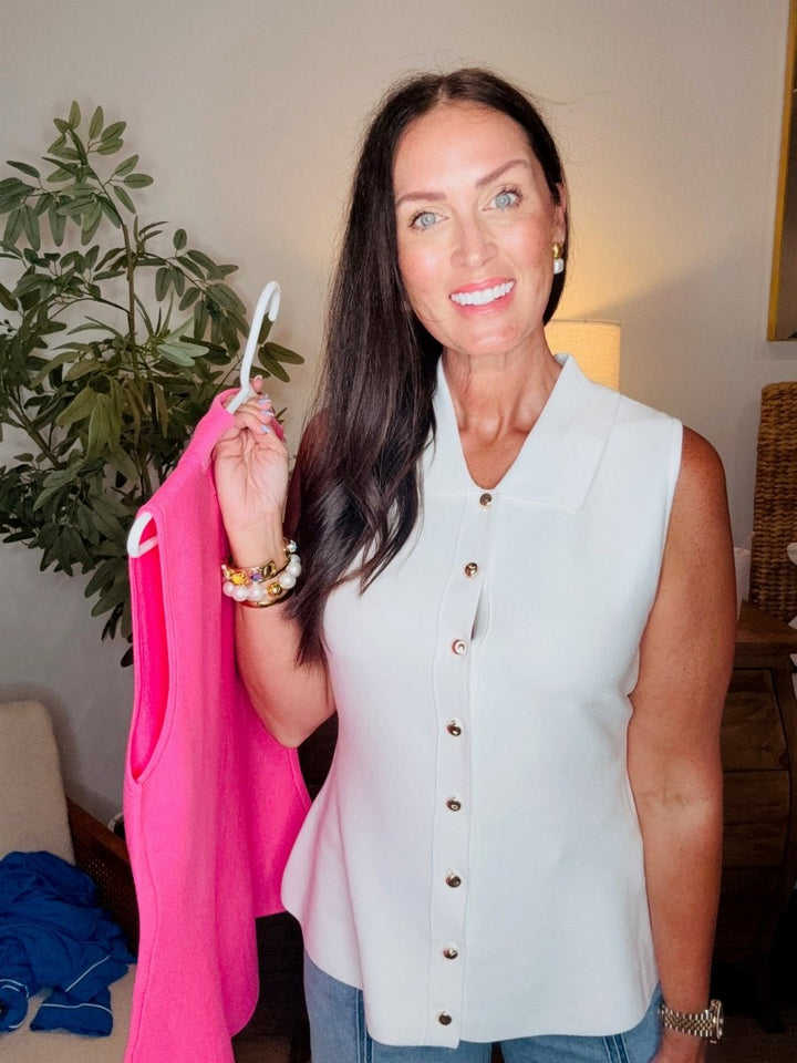 Woman holding a pink jacket indoors with a plant and lamp in the background