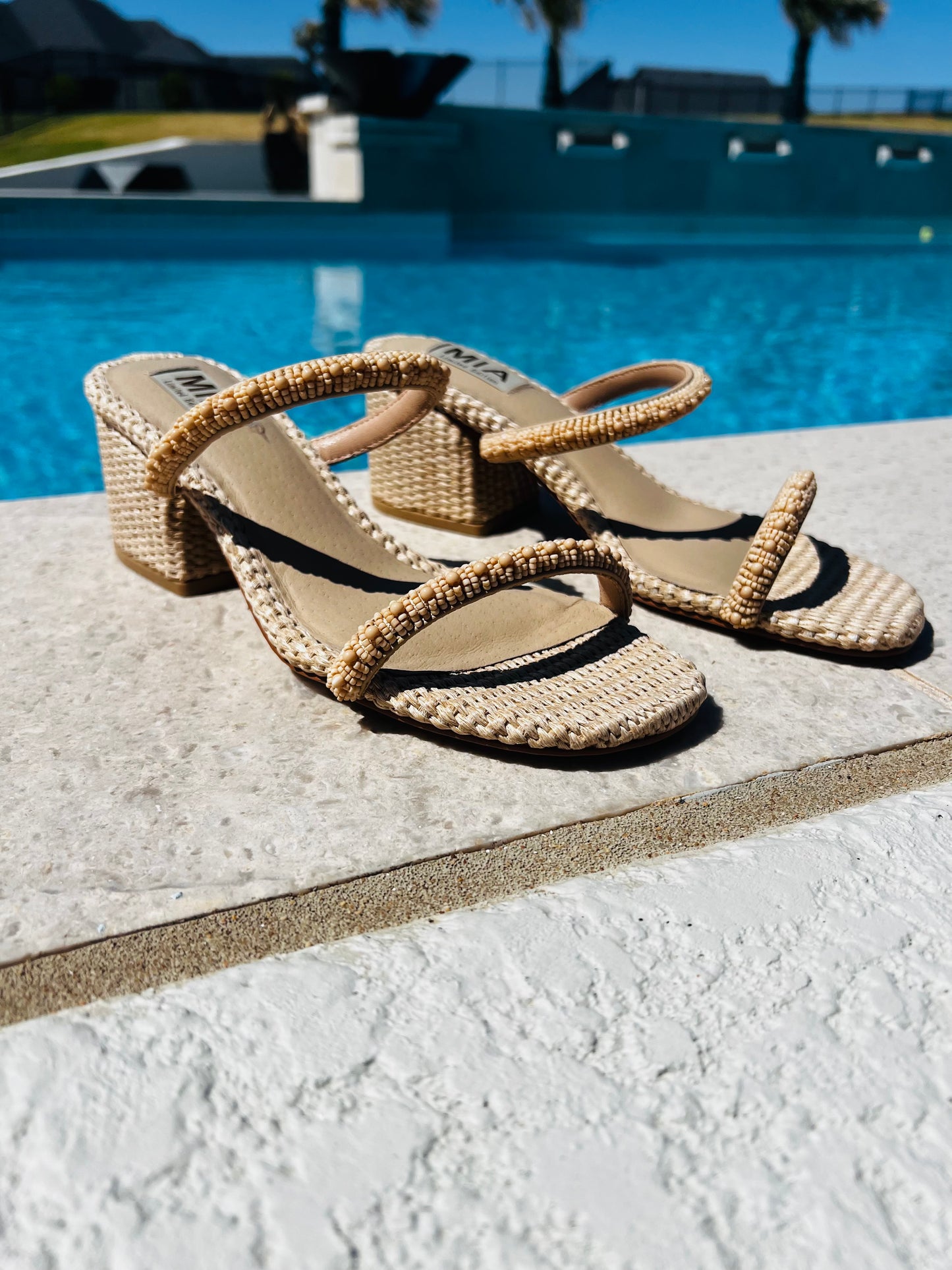 Pair of woven sandals on a ledge near a pool