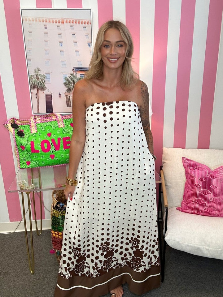 woman standing in a living room in a brown and white polkadot dress