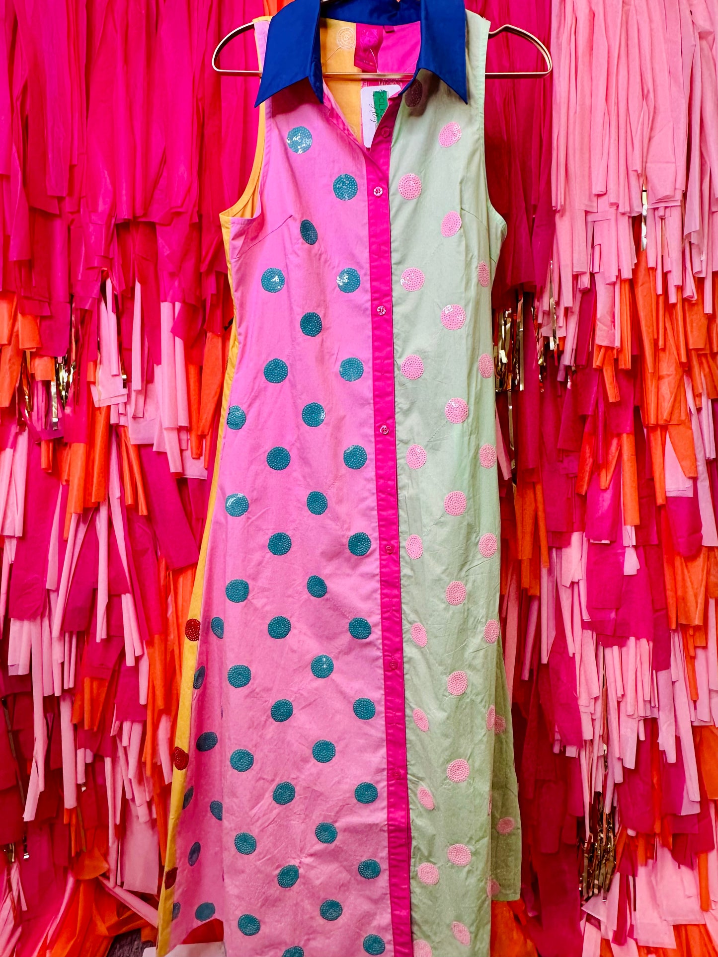 Two dresses with polka dot patterns hanging against a colorful background