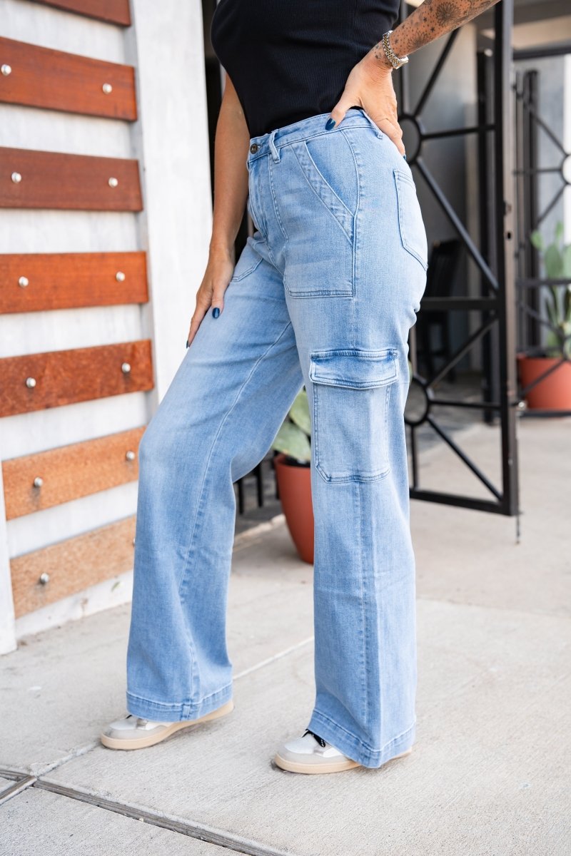 Person wearing light blue patchwork jeans standing against a wall with wooden slats.