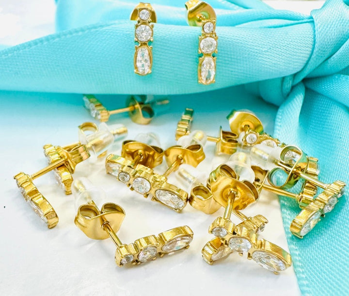 Collection of gold earrings on a turquoise fabric background
