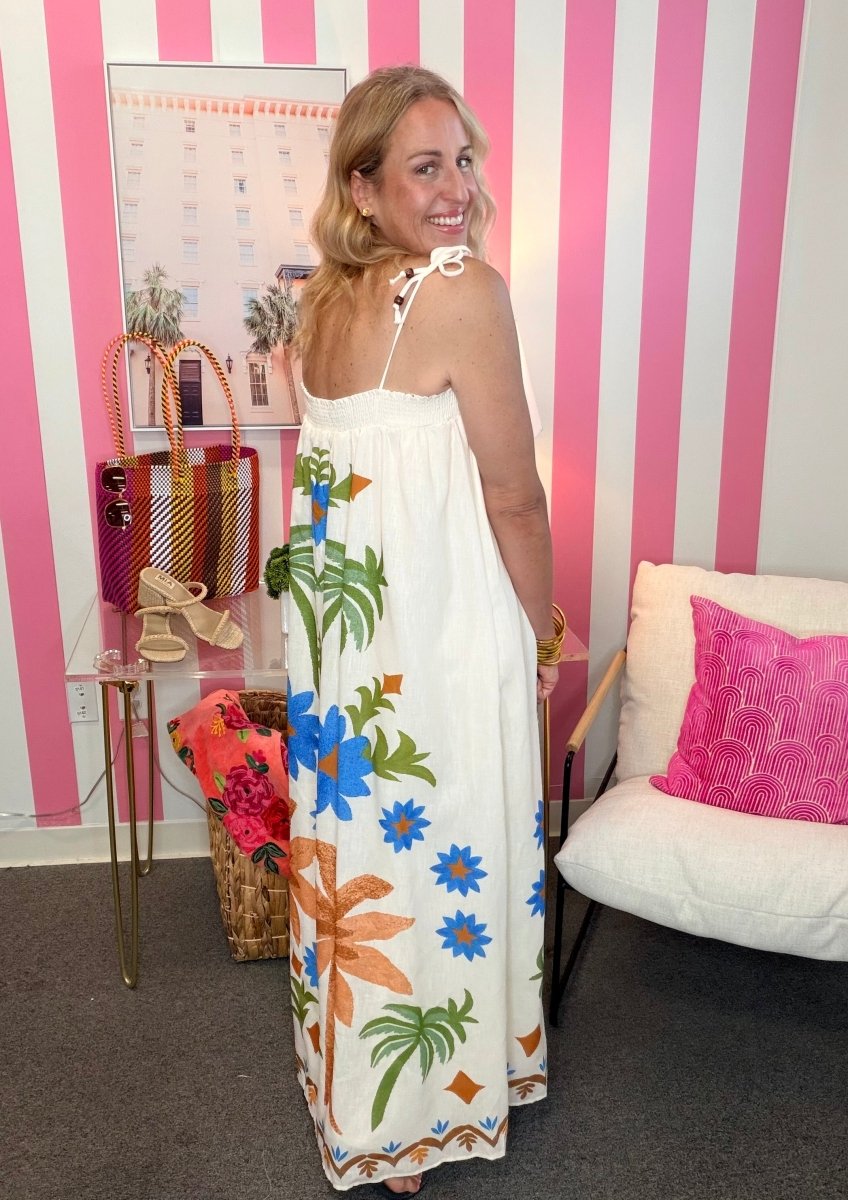 Woman in a floral dress standing in a room with pink and white striped walls.